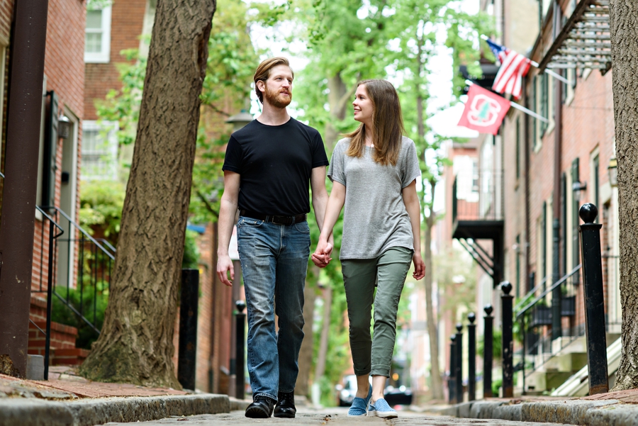 A couple walk down their city street in center city Philadelphia for their engagement session.